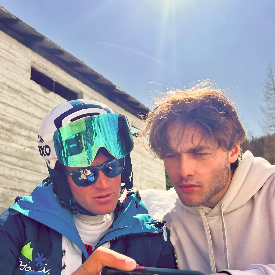 A coach and athlete review a video after a session on the snow